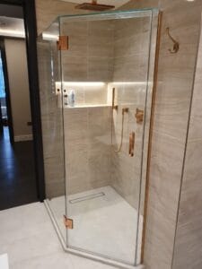 Bespoke glass shower enclosure with polished cooper fittings in South West London
