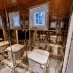 Full height antique mirror wall installation in a narrow toilet
