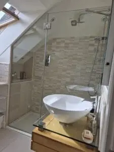 Bespoke glass shower enclosure for a sloping ceiling in a London loft bathroom
