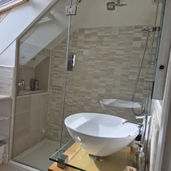 Bespoke glass shower enclosure for a sloping ceiling in a London loft bathroom