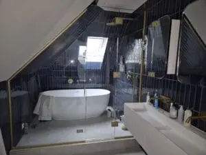 Glass shower enclosure installed under a sloping ceiling in a modern loft bathroom