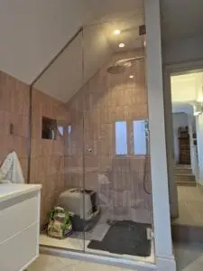 Bespoke shower glass enclosure for sloping ceiling with chrome fittings