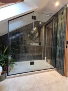 Modern frameless glass shower enclosure with black fittings installed in London