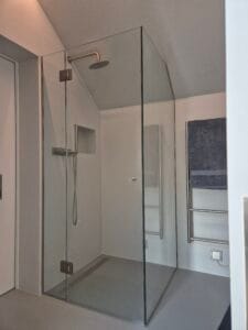 Bespoke glass shower enclosure designed for sloping ceiling loft bathroom in London