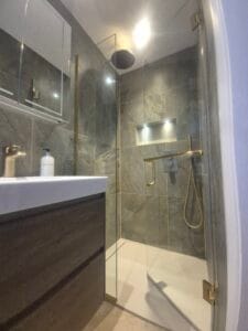 Frameless glass shower enclosure with brushed brass fittings installed in London